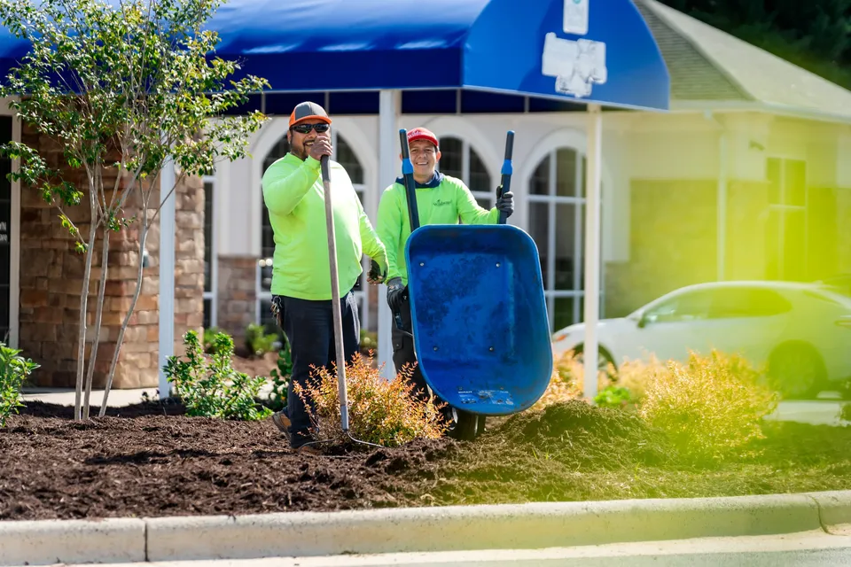 Wildwood Landscapes crew spreading mulch at a commercial building entrance.
