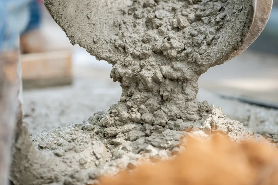 Wet concrete pouring into a sidewalk form on a commercial hardscape job.
