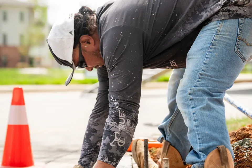 Finisher edging a curved concrete sidewalk at a commercial property.