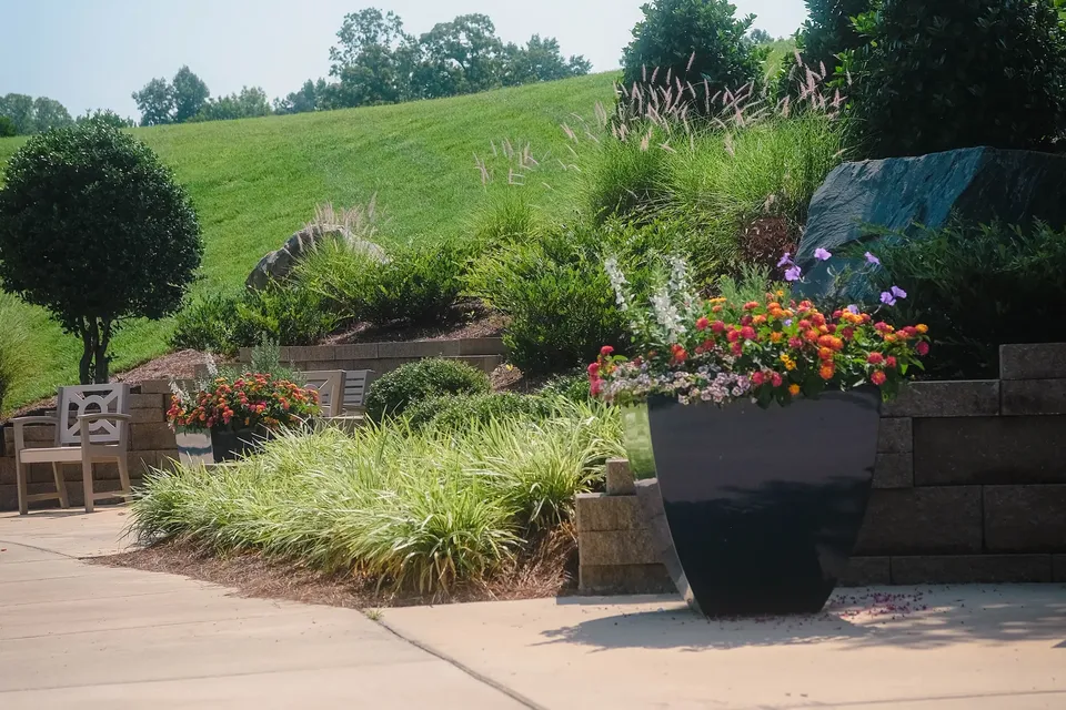 Concrete walk, stone retaining wall, and planted beds on a managed property.
