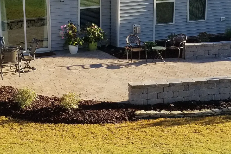 Paver patio with a curved stone seating wall and outdoor seating.