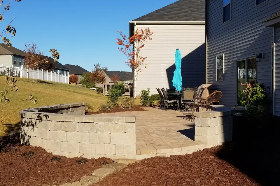 Curved stone retaining wall around a new paver patio.