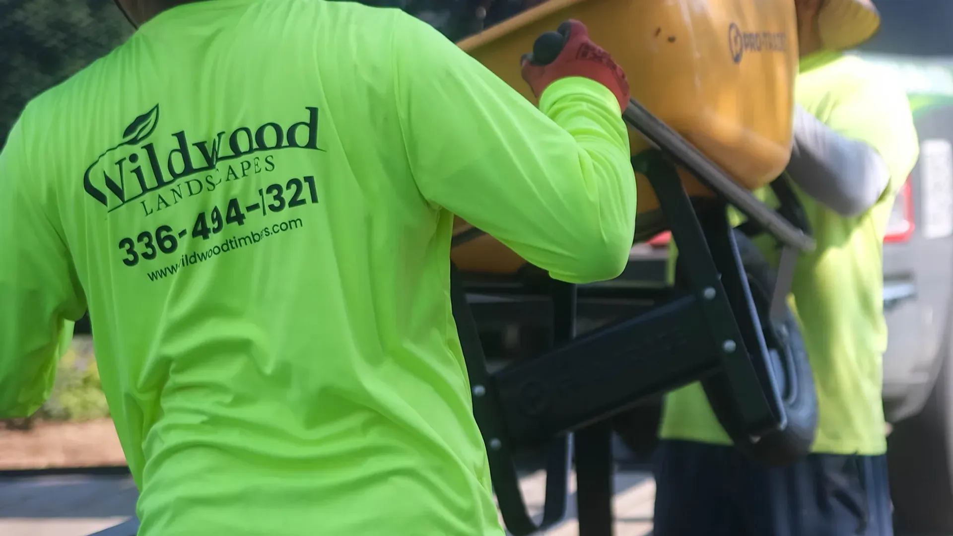Wildwood Landscapes crew loading a wheelbarrow onto a work trailer.