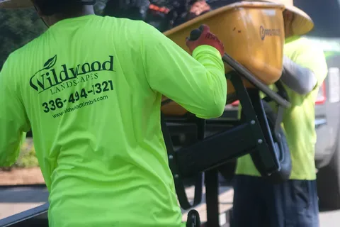 Wildwood Landscapes crew loading a wheelbarrow onto a work trailer.